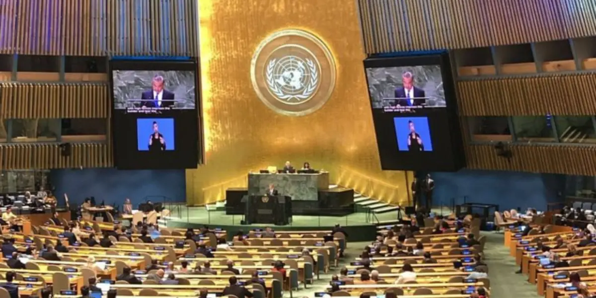 Assemblea Generale delle Nazioni Unite con intervento dal podio e simbolo ONU sullo sfondo.