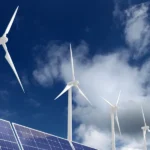 L'immagine mostra una pianura con pannelli solari e impianti eolici